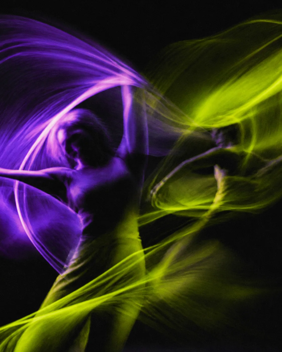 Purple and lime light trails creating an abstract motion scene.